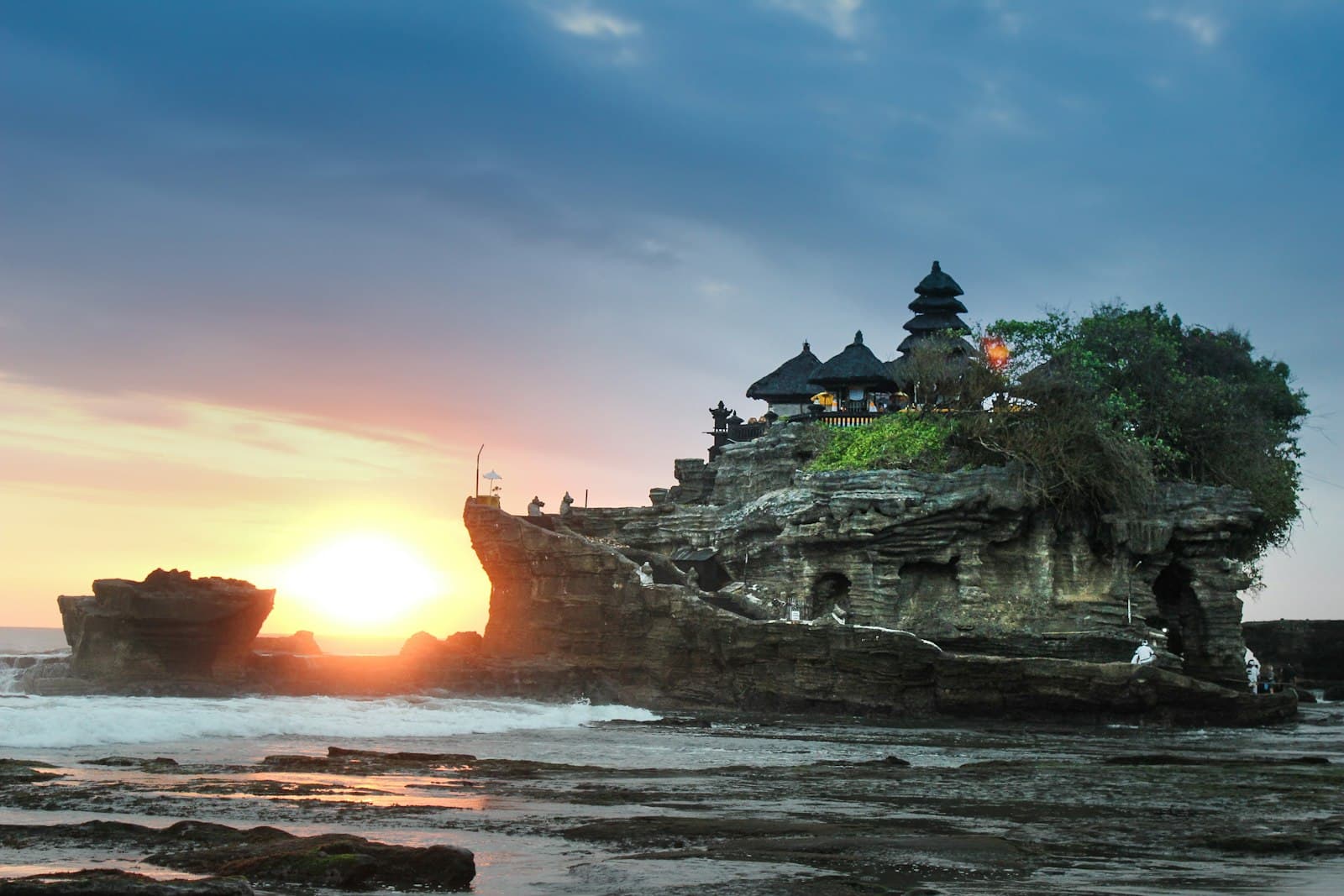 Pura laut Tanah Lot bersiluet di depan matahari terbenam keemasan Bali — malam pertama klasik di pulau ini.