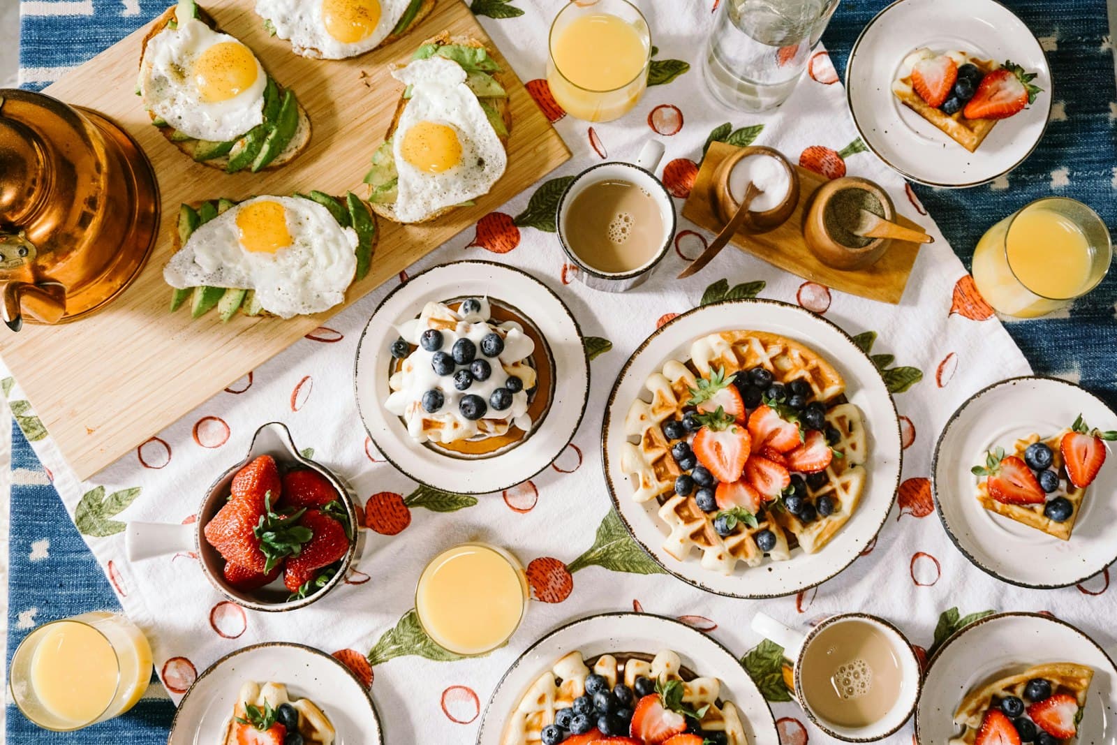 A generous breakfast spread with waffles, fresh fruit, eggs and coffee.